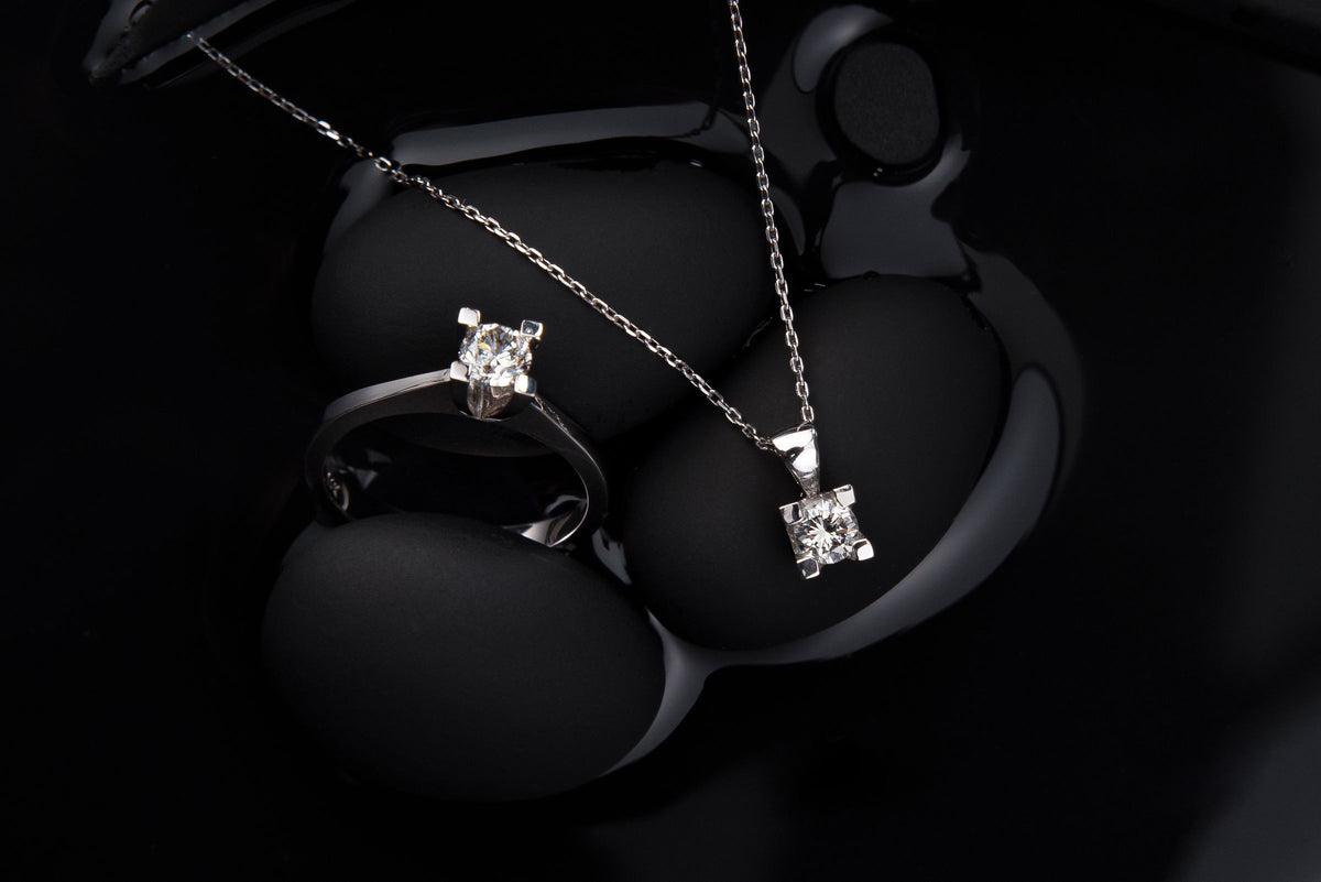 Anillo y colgante de plata sobre fondo negro